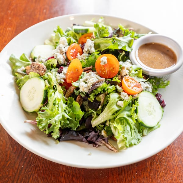 Fresh garden salad with mixed greens, cherry tomatoes, cucumbers, blue cheese, and dressing.