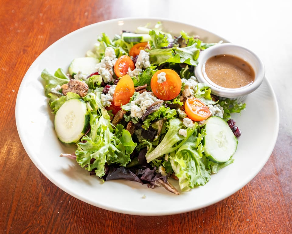 Fresh garden salad with mixed greens, cherry tomatoes, cucumbers, blue cheese, and dressing.